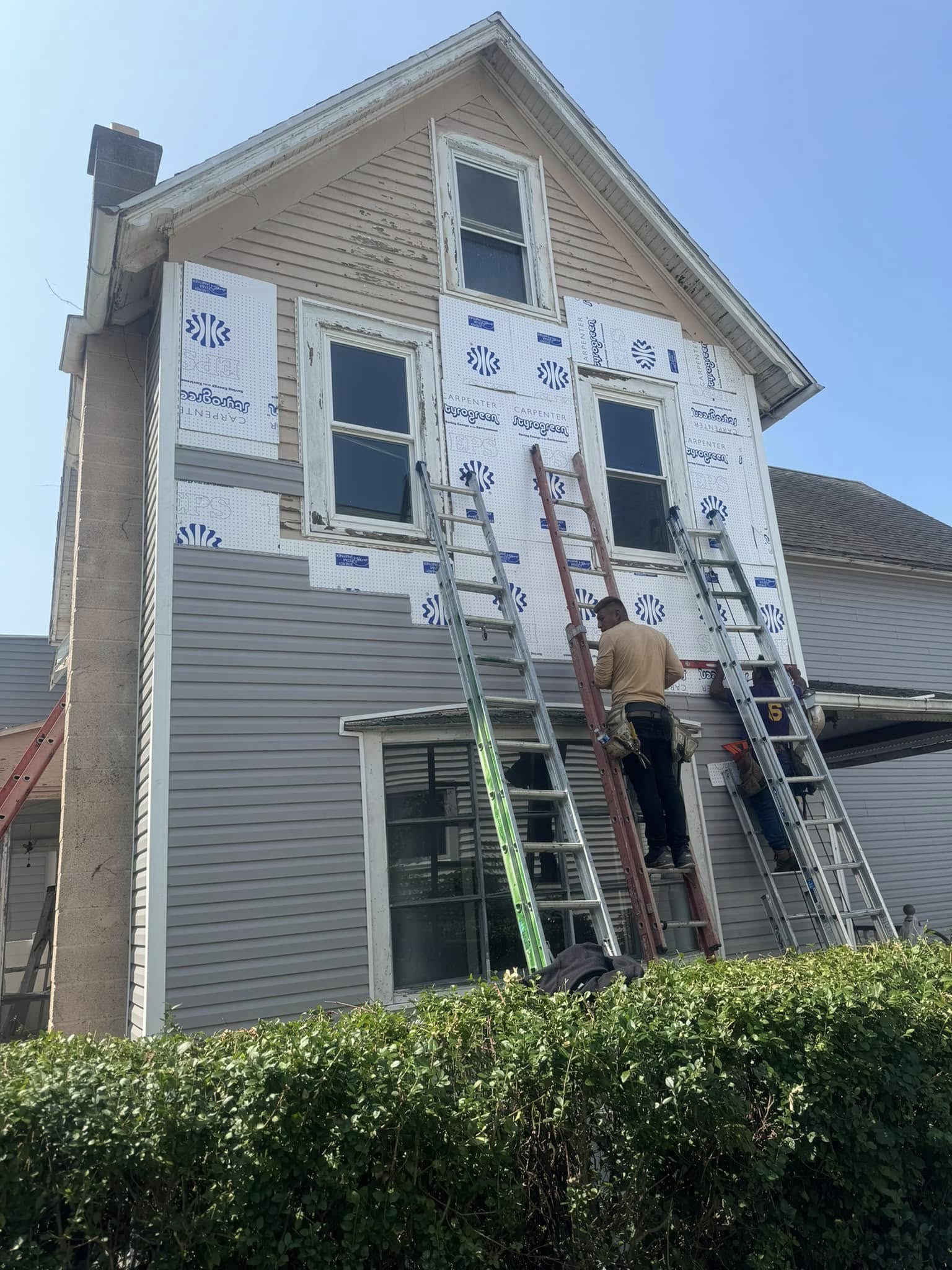 Vinyl siding installation project showing house wrap and exterior renovation in progress